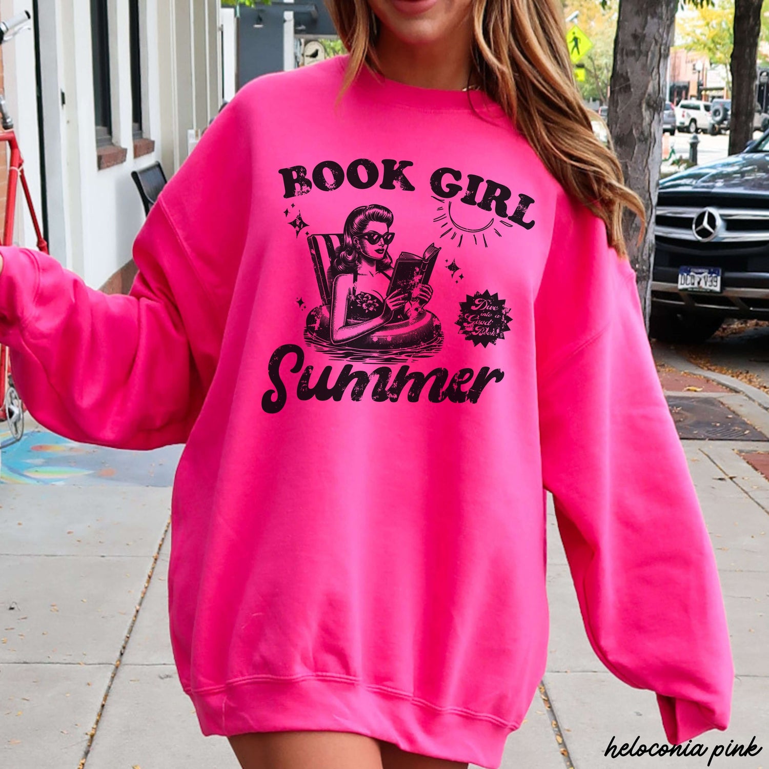 Book Girl Summer Sweatshirt 5 Colors S-3X in bright pink with a fun graphic design worn by a woman outdoors.